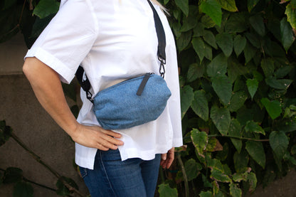 Person wearing denim belt bag with black crossbody/belt bag strap with black leather detail