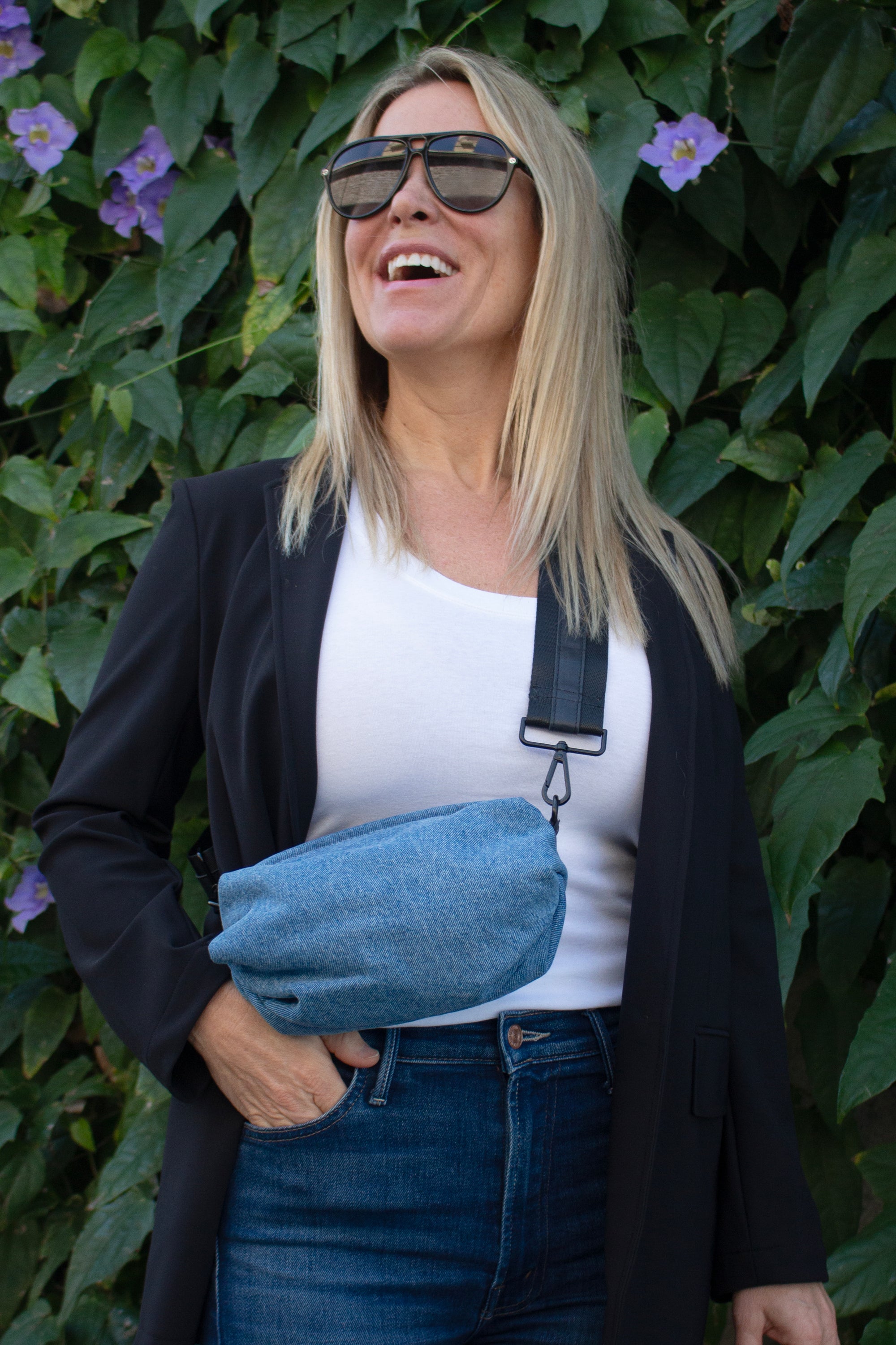 Person wearing denim belt bag with black crossbody/belt bag strap with black leather detail