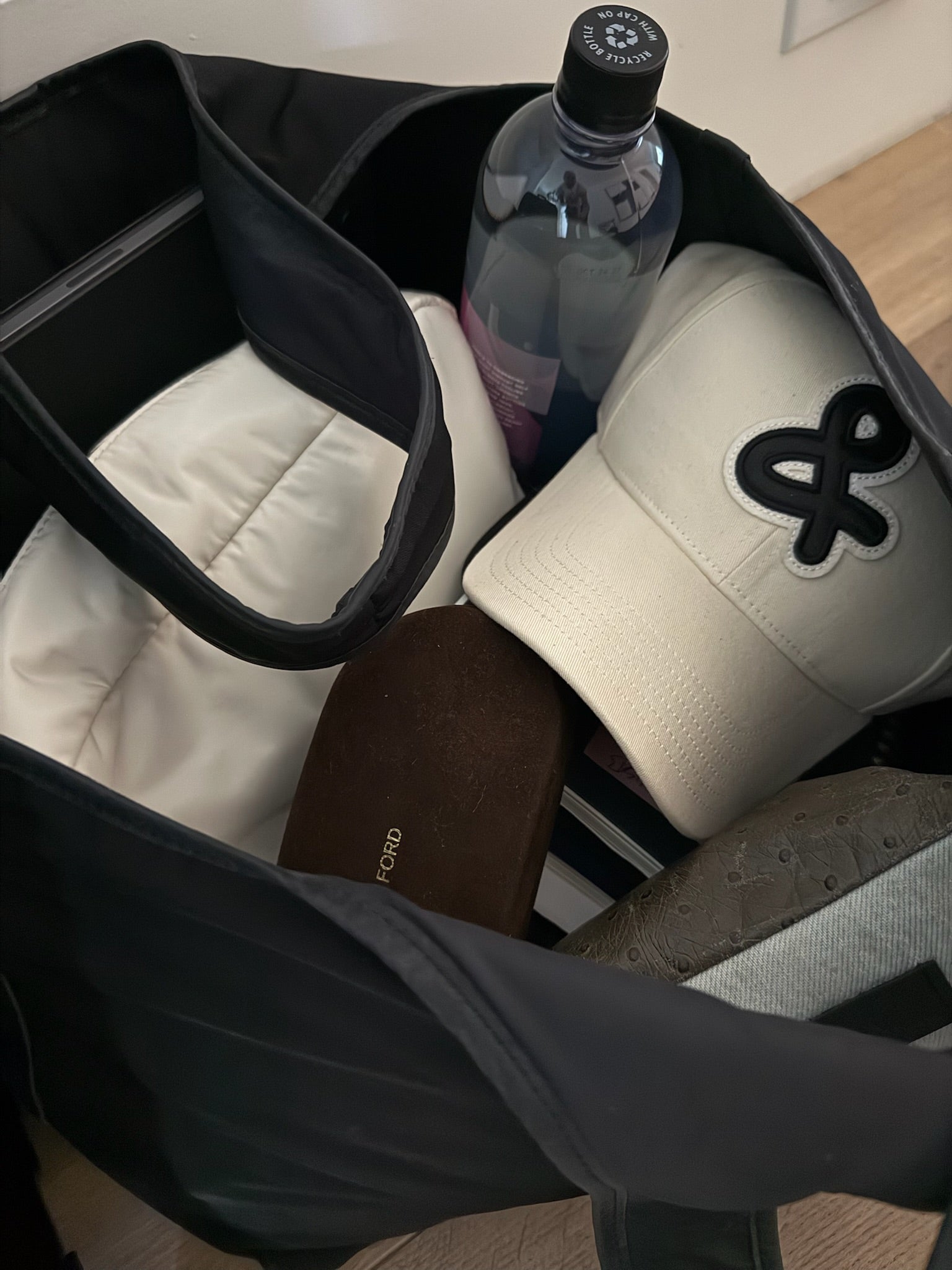 Close-up of a bag with a cream basehat, water bottle and sunglasses inside.