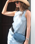 Person wearing denim belt bag with black crossbody/belt bag strap with black leather detail