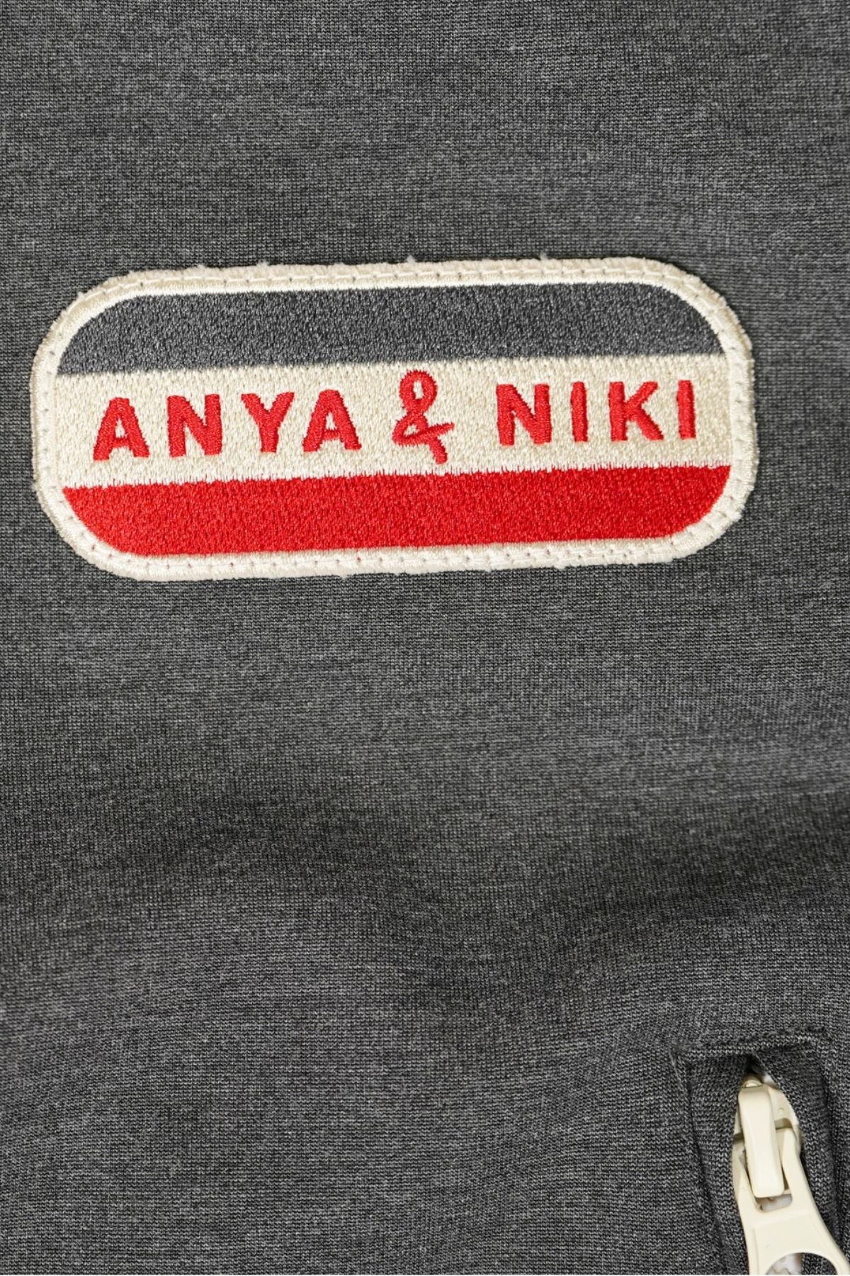 Close up of a gray jacket with 'Anya &amp; Niki' logo patch.