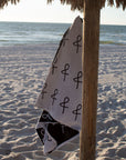 Anya & Niki large beach towel hanging from a cabana pole at the beach