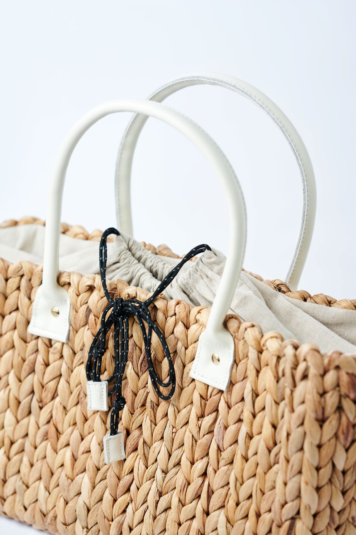close-up of top of medium natural hyacinth straw tote with linen cinch top
