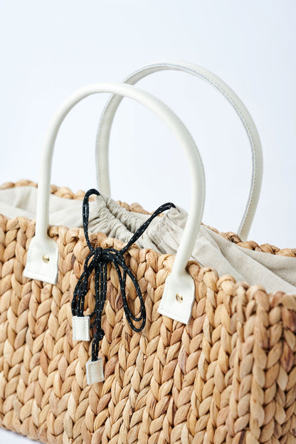 close-up of top of medium natural hyacinth straw tote with linen cinch top