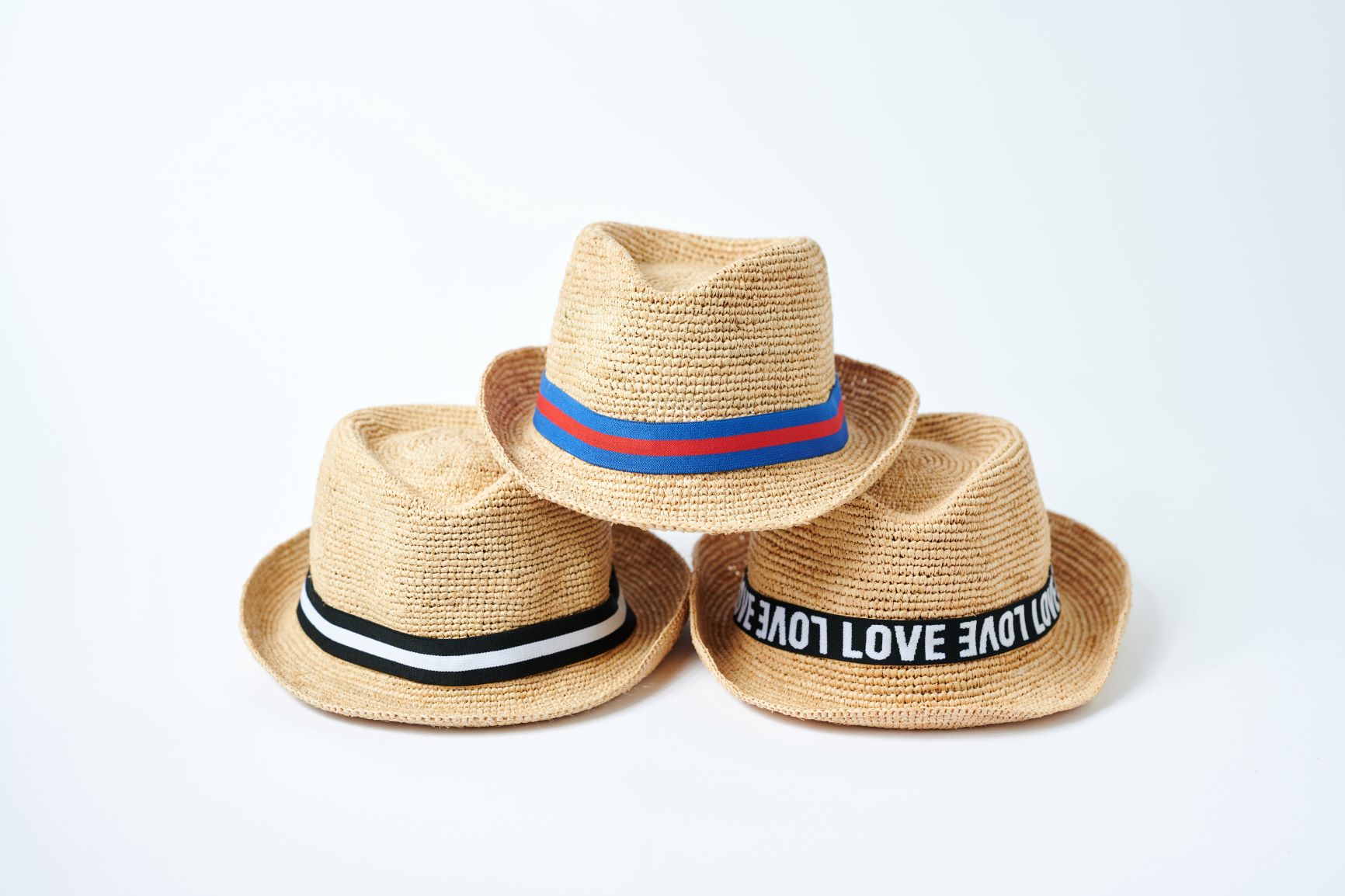 Stack of three Anya &amp; Niki Essential straw hats with different bands. 