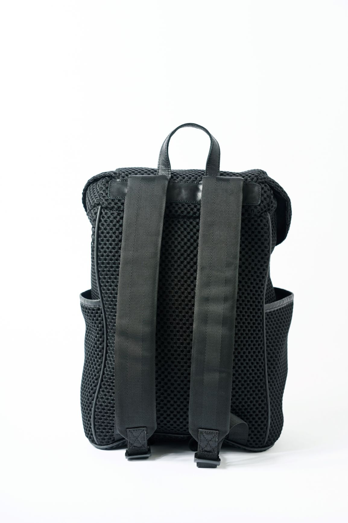 Back view of a black mesh backpack with leather details and shiny silver drawstring top.