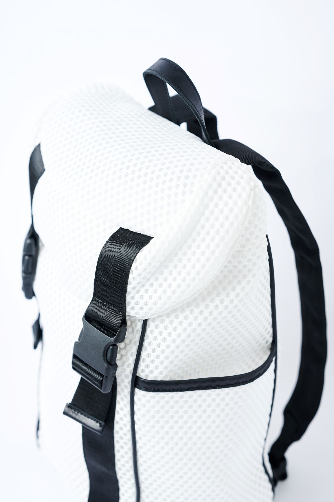 Close up of flap top on white mesh backpack with leather details and clear drawstring top.
