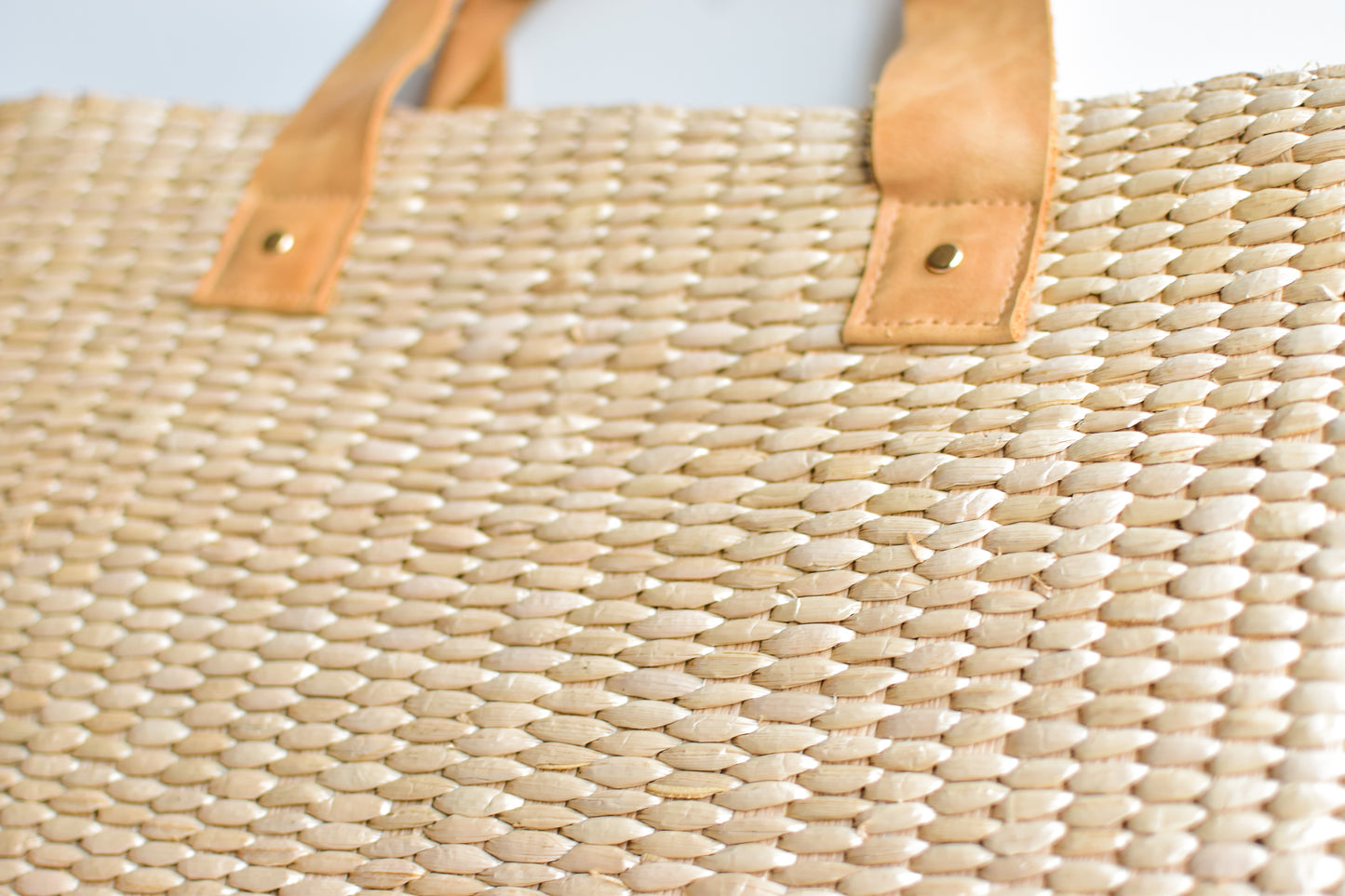 Large straw tote bag finished with natural leather handles and linen lining. 