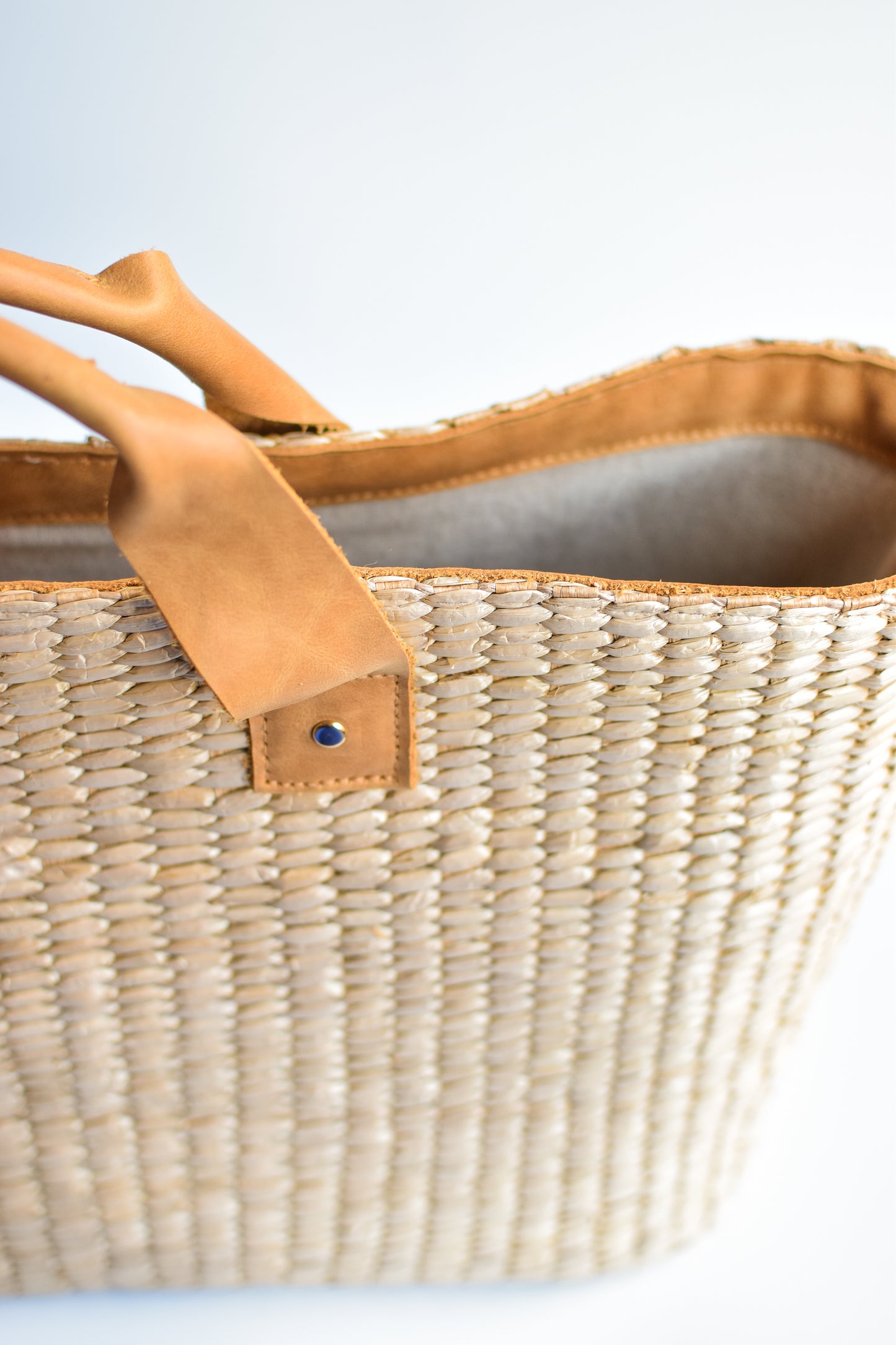 Large straw tote bag finished with natural leather handles and linen lining. 