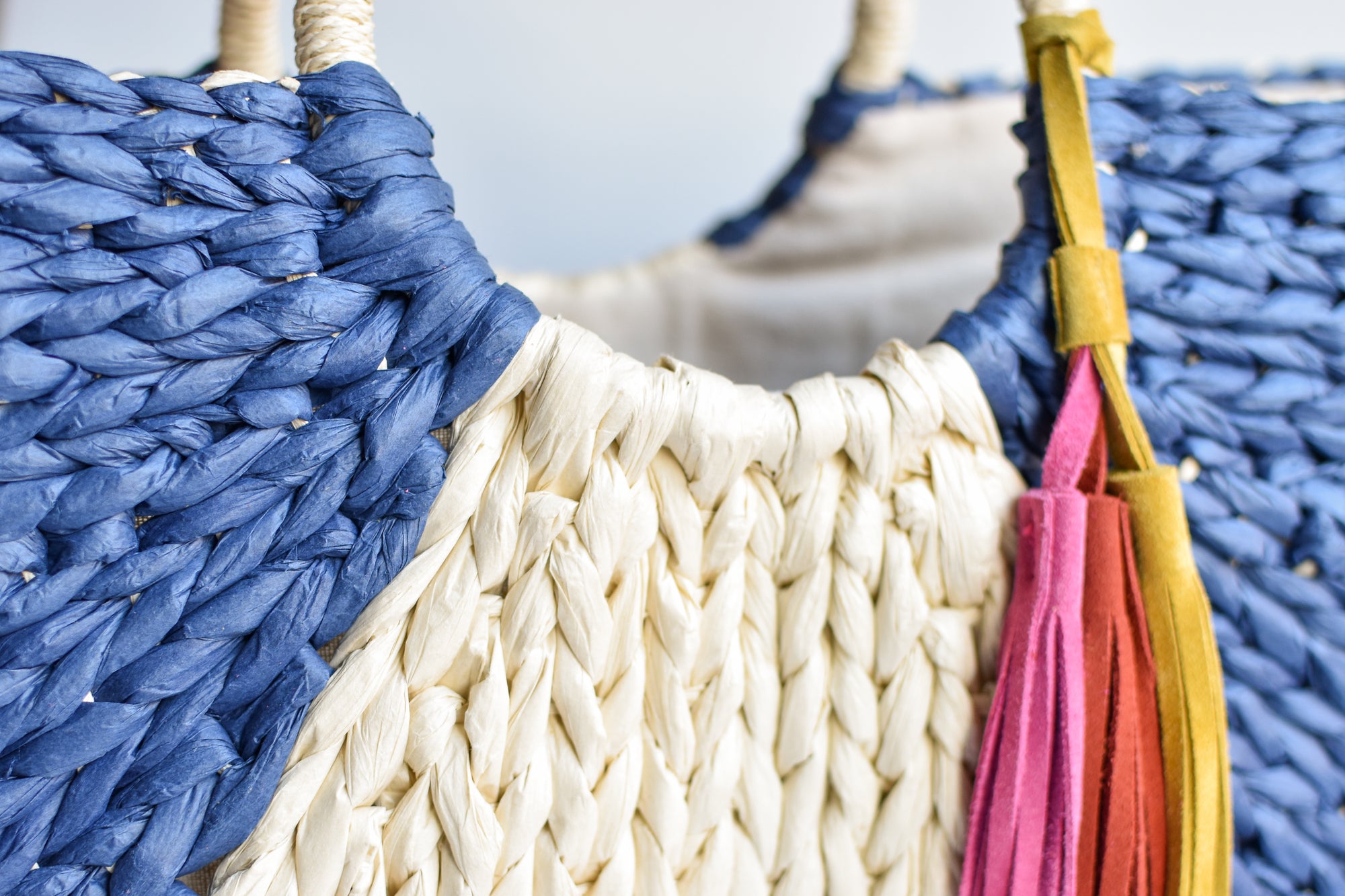 Navy and natural colored over-sized straw tote with circle handle and suede tassels.