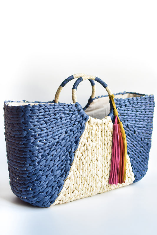 Navy and natural colored over-sized straw tote with circle handle and suede tassels.