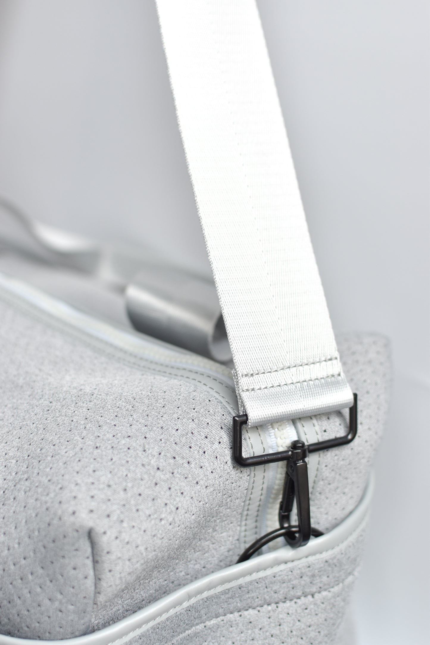 Close up of side pocket and cross-body strap on the Callahan light gray perforated neoprene duffel bag.