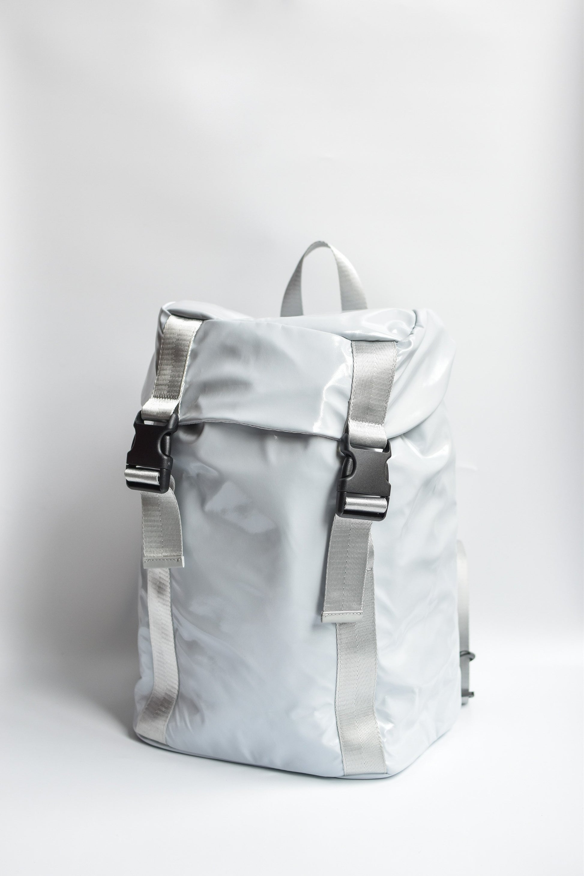 Gray high gloss backpack with gray leather and webbing details. 