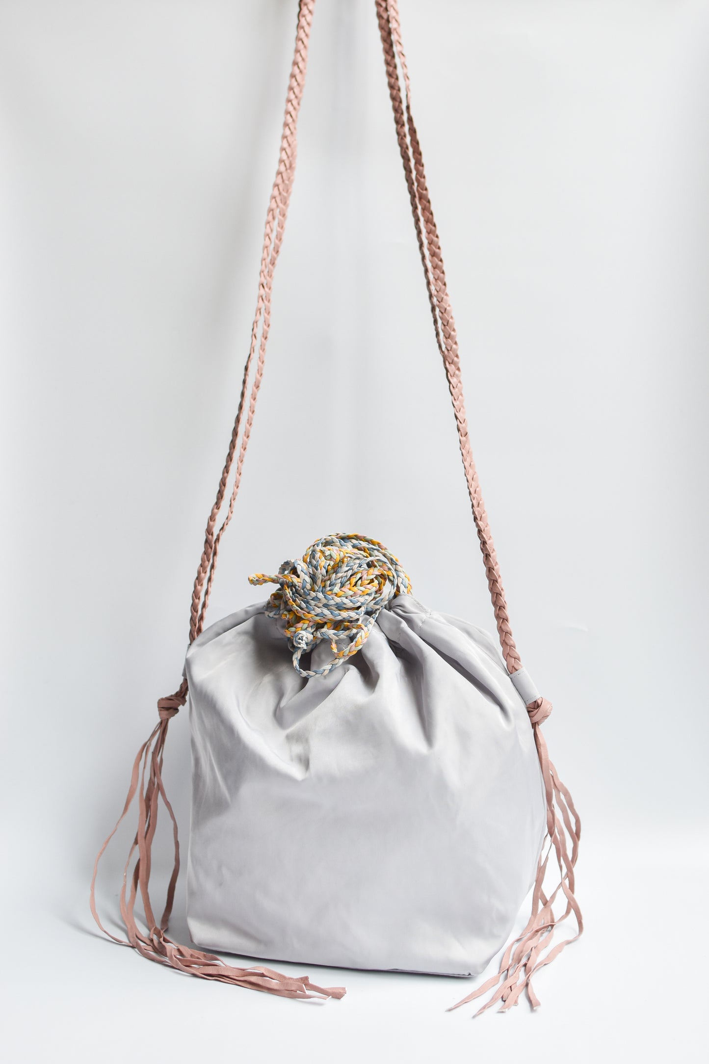Sporty gray nylon cinch bag with colorful braided leather straps. 