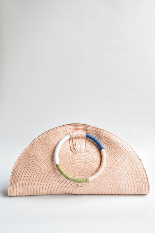 Pink half-moon straw clutch with colorful wrapped circle handle and leather sides.