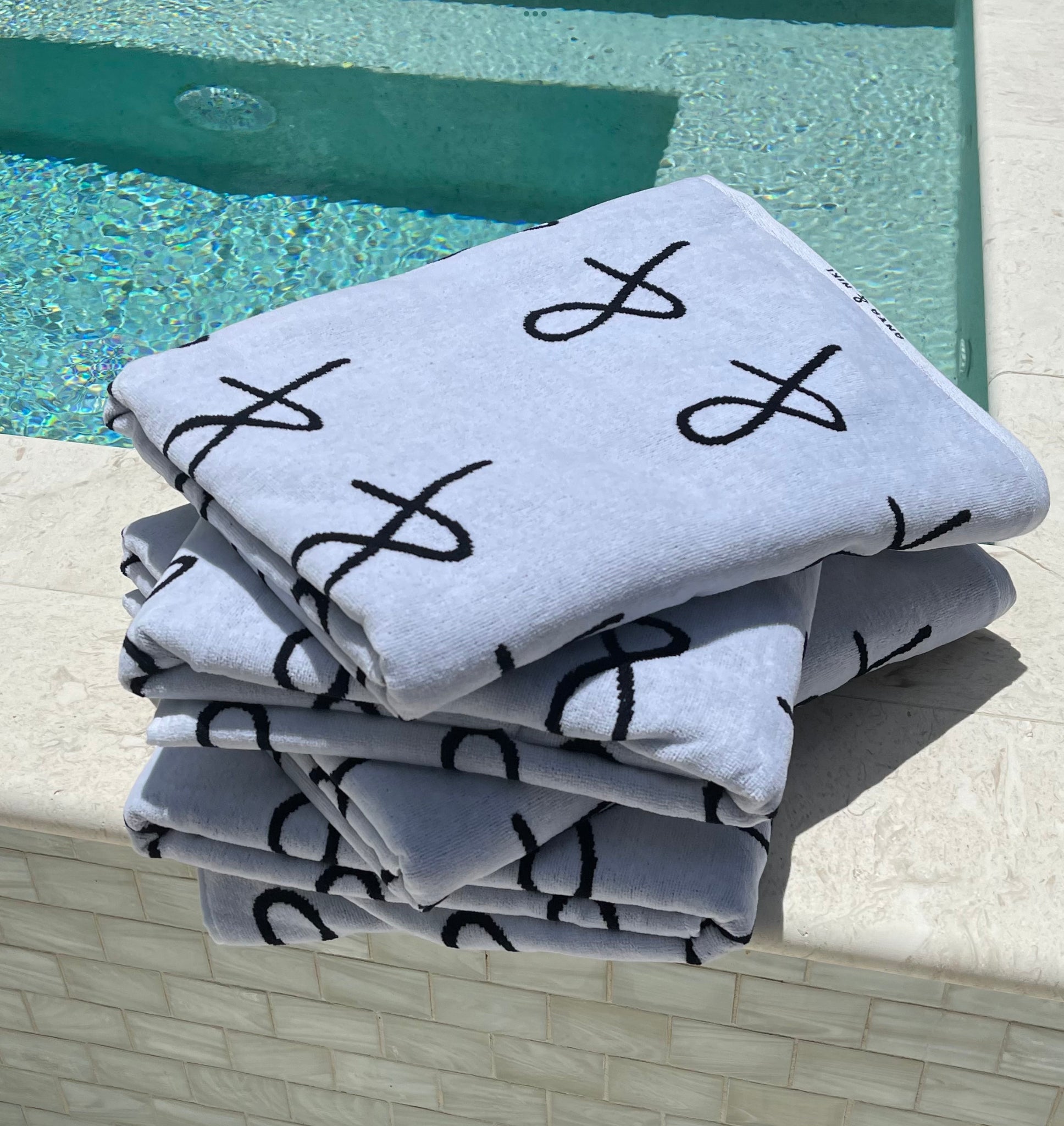 stack of Anya &amp; Niki beach towels on the edge of the pool