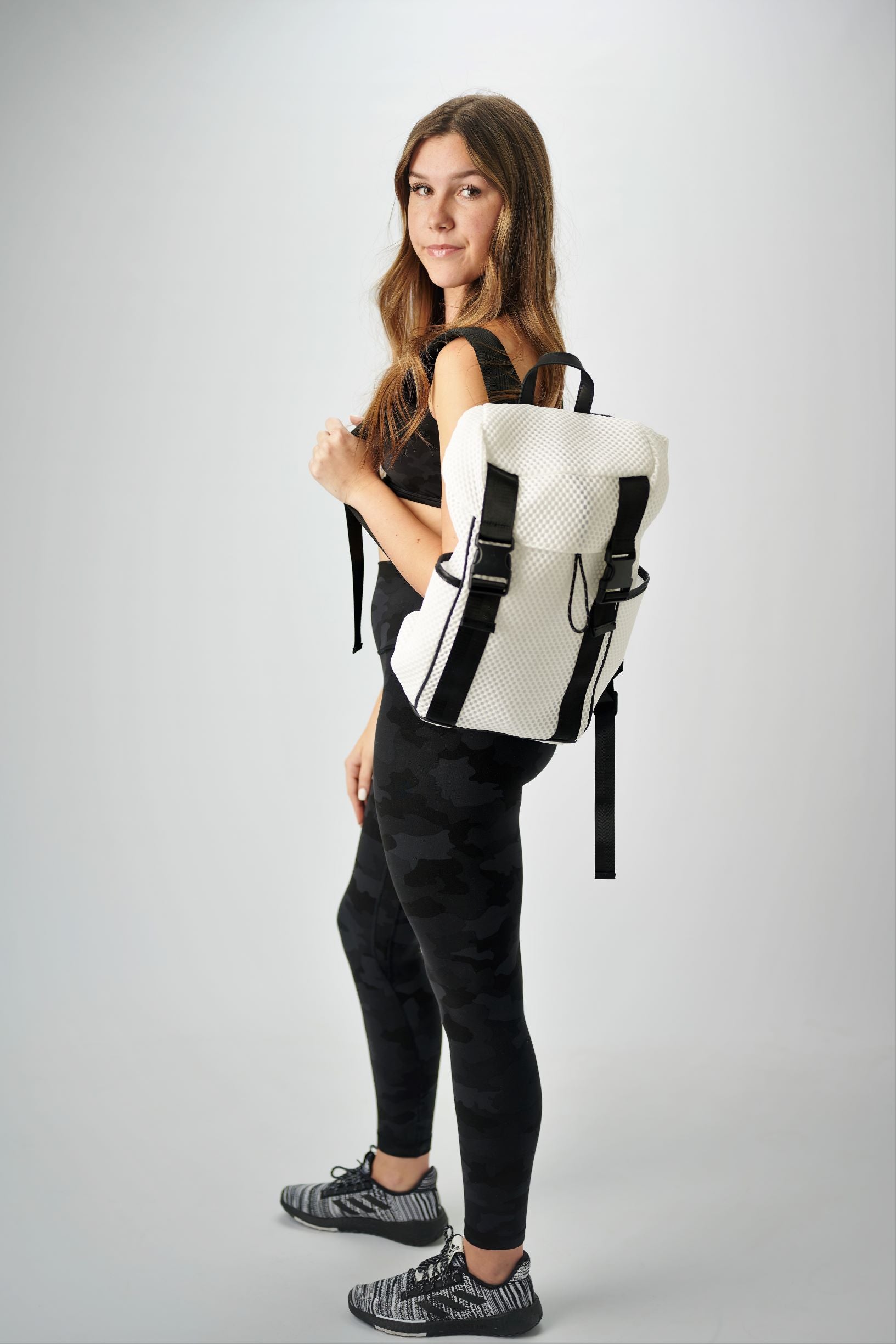 Person holding the Anya & Niki Newberry Backpack - a white mesh backpack with leather details and clear drawstring top.