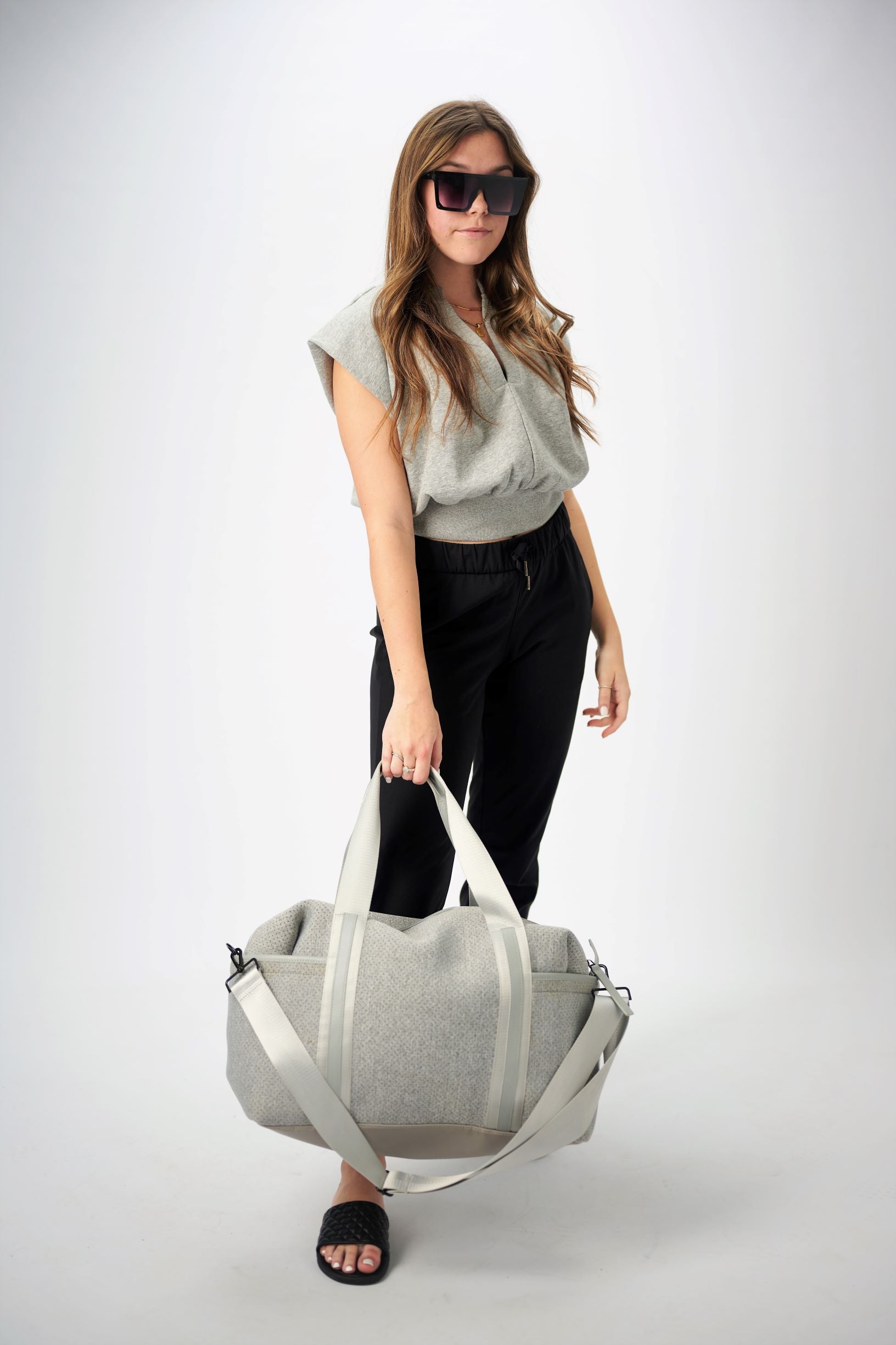 Person holding the Callahan light gray perforated neoprene duffel bag with leather details.