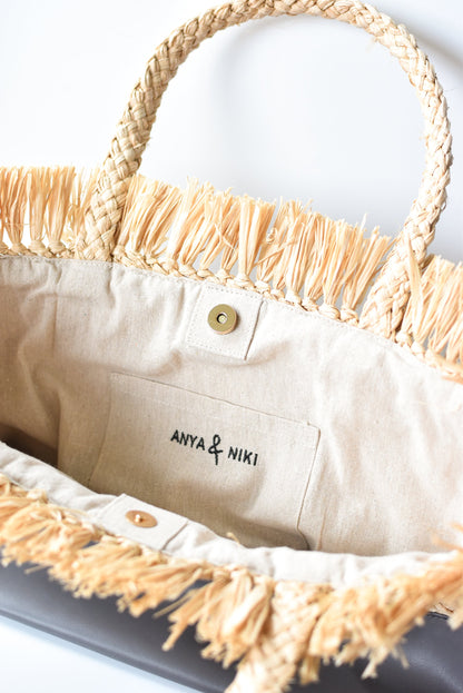 Close up of interior linen lining on natural raffia straw tote with gray color block base.