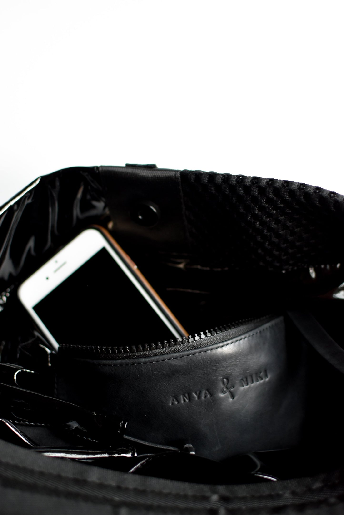 Close up of interior leather pocket on black sporty mesh and shiny vinyl tote bag.
