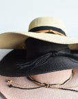 Stacked floppy straw hat collection, featuring a black floppy straw hat, pink floppy straw hat and natural colored floppy straw hat.