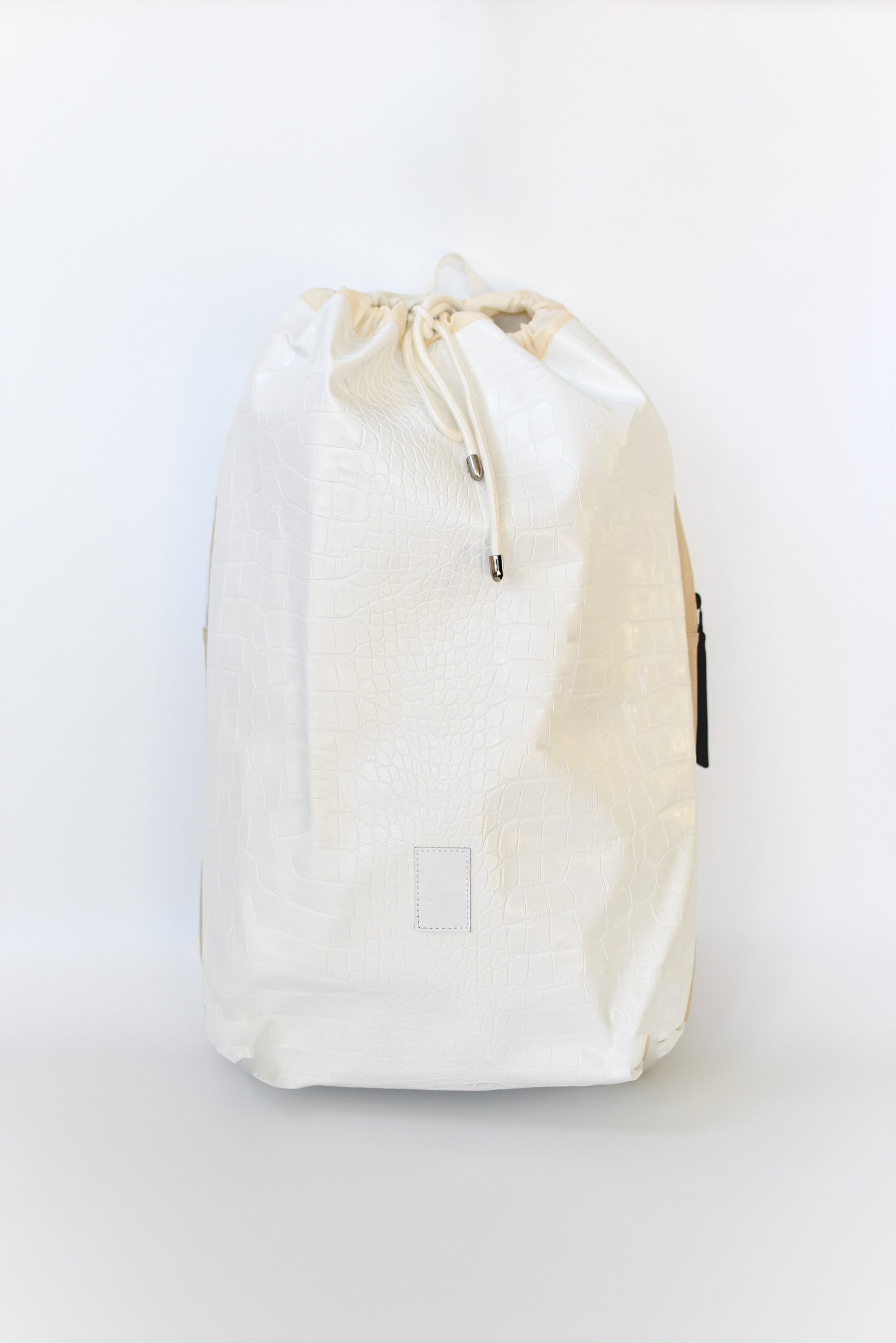 Off white faux croc embossed Casselberry backpack with cinch top and back zipper compartment.