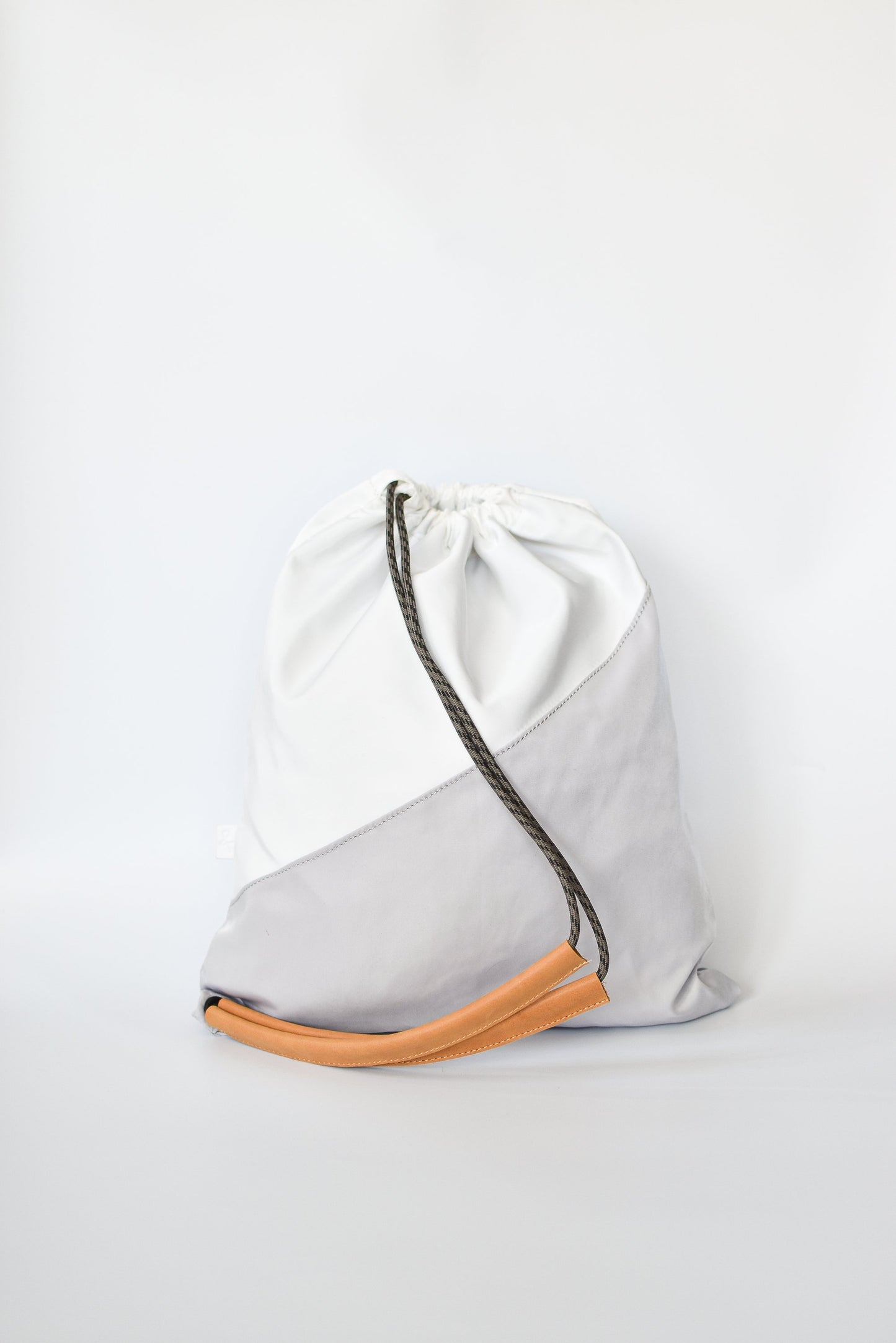 Sporty nylon sling bag in white and gray with natural leather straps. 