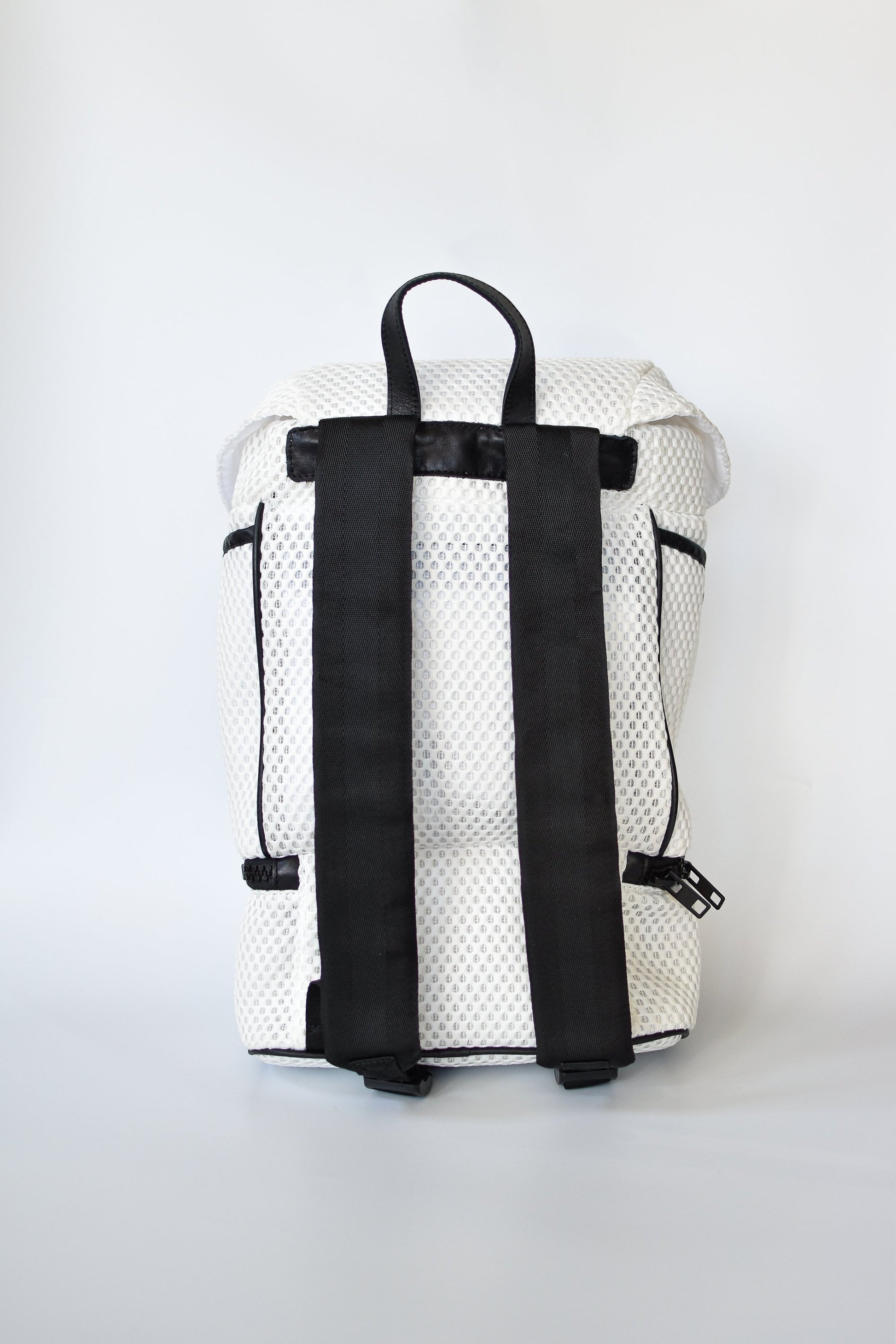 Back view of Brooker white mesh backpack with black front straps and bottom zipper compartment with black chunky zipper. 