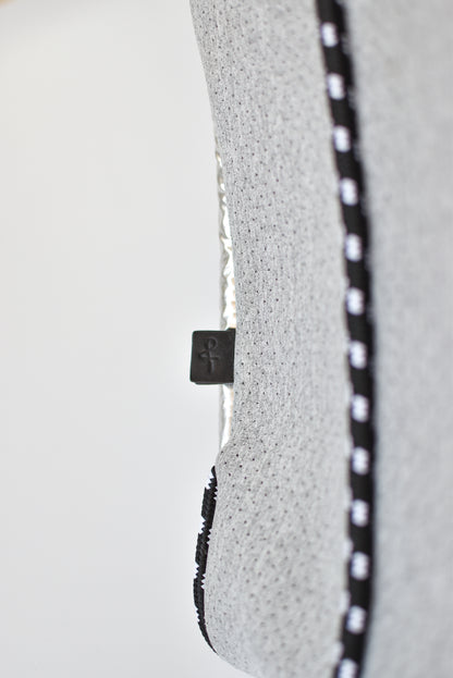Close up of leather logo tab and cording detail on perforated gray neoprene tote bag.