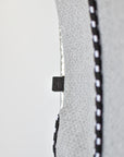 Close up of leather logo tab and cording detail on perforated gray neoprene tote bag.