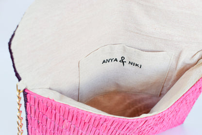 Interior linen lining on pink woven raffia straw clutch. 