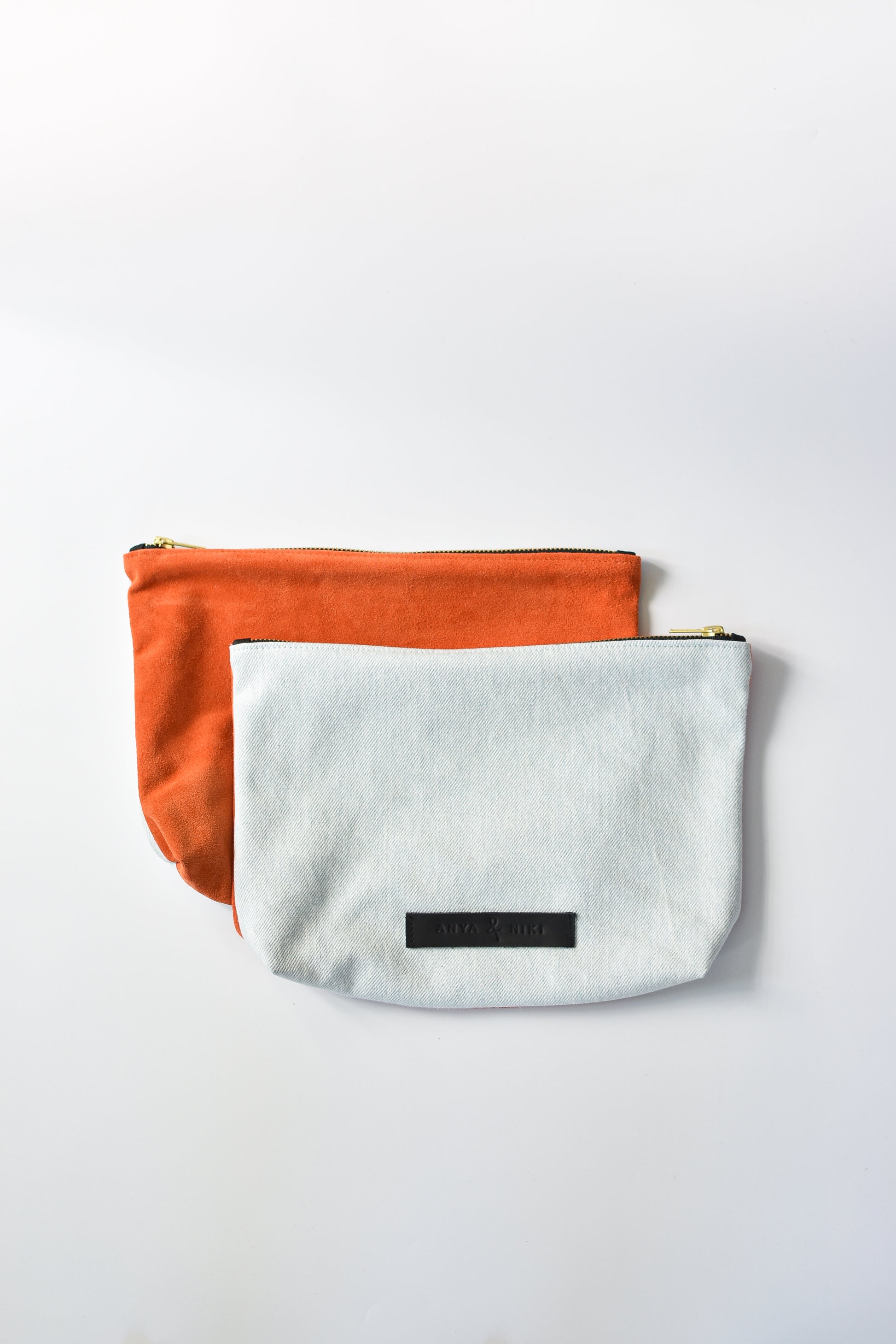 Washed denim and orange suede medium sized pouch with brass zipper and leather logo label.