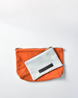 Washed denim and orange suede medium and small pouch with brass zipper and leather logo label.