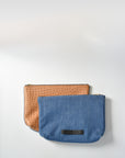 Medium wash denim and caramel colored embossed leather skin medium pouch with brass zipper and leather logo label.