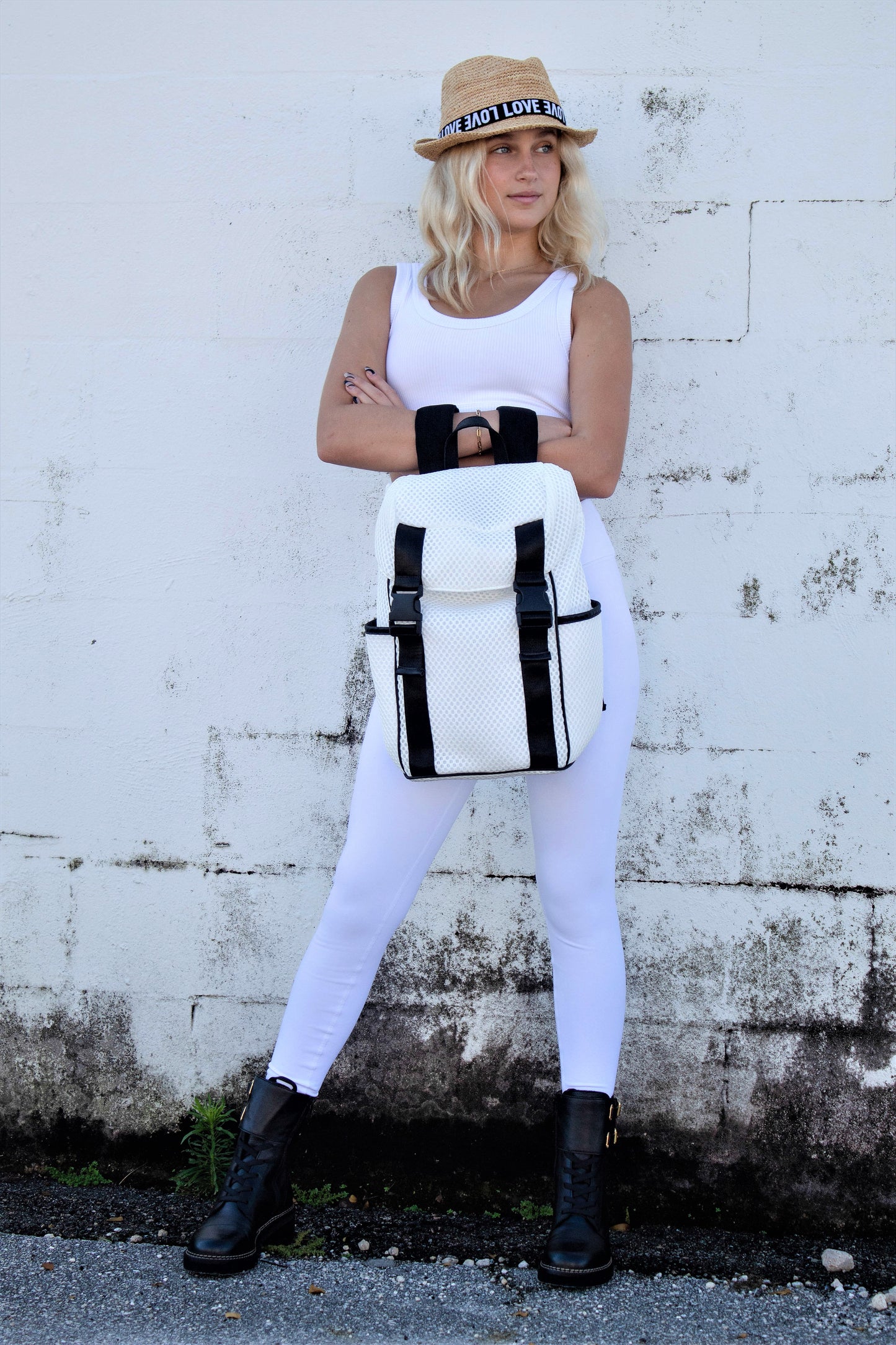 Person holding the Anya & Niki Newberry Backpack - a white mesh backpack with leather details and clear drawstring top.