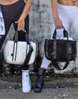 Two people holding The MIdway Tote in black and white.