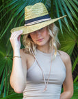 Person wearing the Tower Hat - a straw lifeguard hat with tan leather chin strap and black band detail.