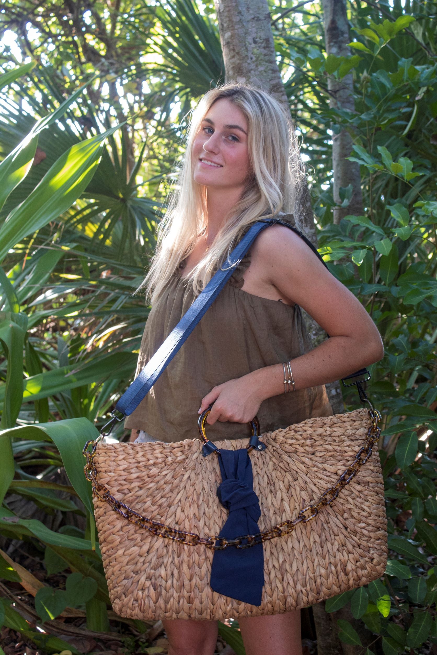 person holding extra-large hyacinth straw tote with torte and navy accents.