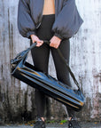 person holding Anya & Niki glossy black yoga mat bag