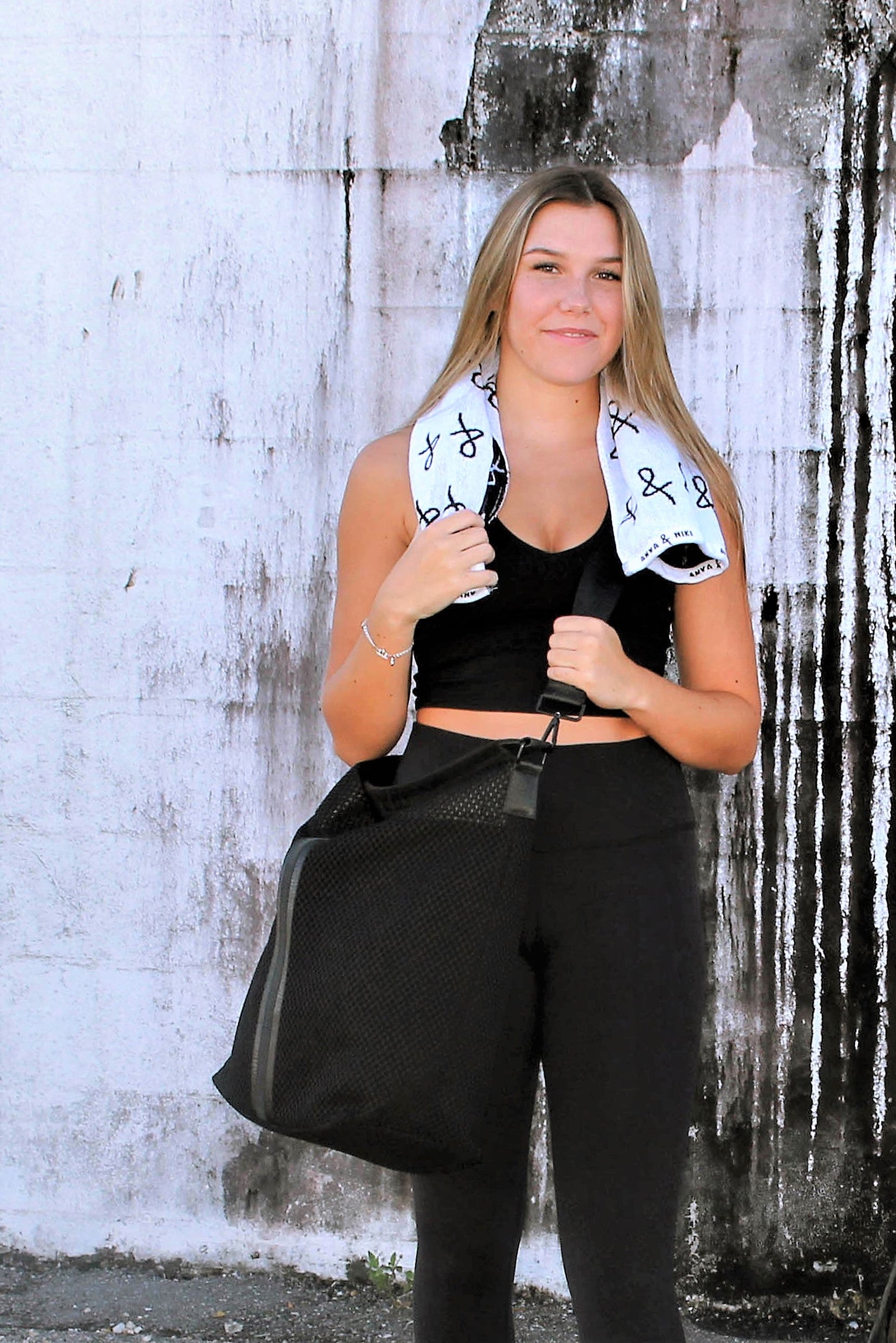 Person holding black sporty mesh tote bag with black leather and webbing details.