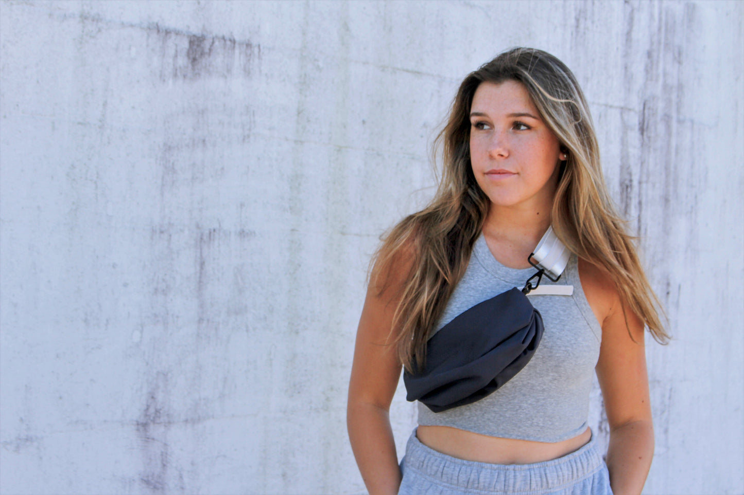 Person wearing navy nylon belt bag with white crossbody strap with white leather detail