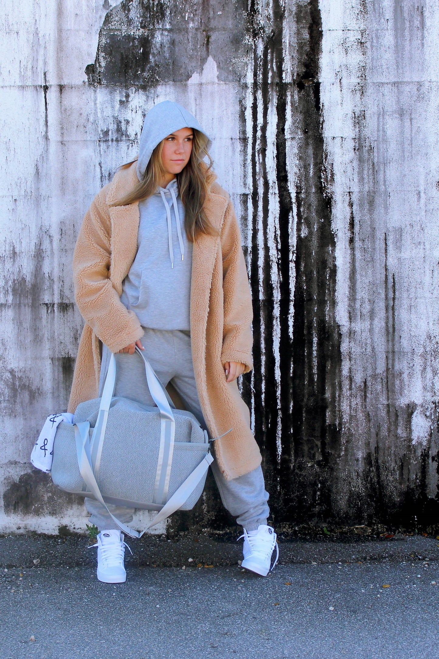 Person holding the Callahan light gray perforated neoprene duffel bag with leather details.