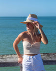 Person wearing the Everywhere Hat - a natural raffia straw panama hat with white grosgrain tie.