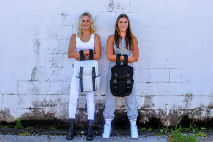 Two people holding Anya & Niki Newberry backpacks in black and white mesh.