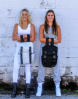 Two people holding Anya & Niki Newberry backpacks in black and white mesh.