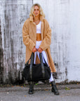 Person wearing the Anya & Niki Stanton Bag - a black mesh duffel bag with leather trim details and black glossy liner.