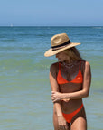 Person wearing the Tower Hat - a straw lifeguard hat with tan leather chin strap and black band detail.