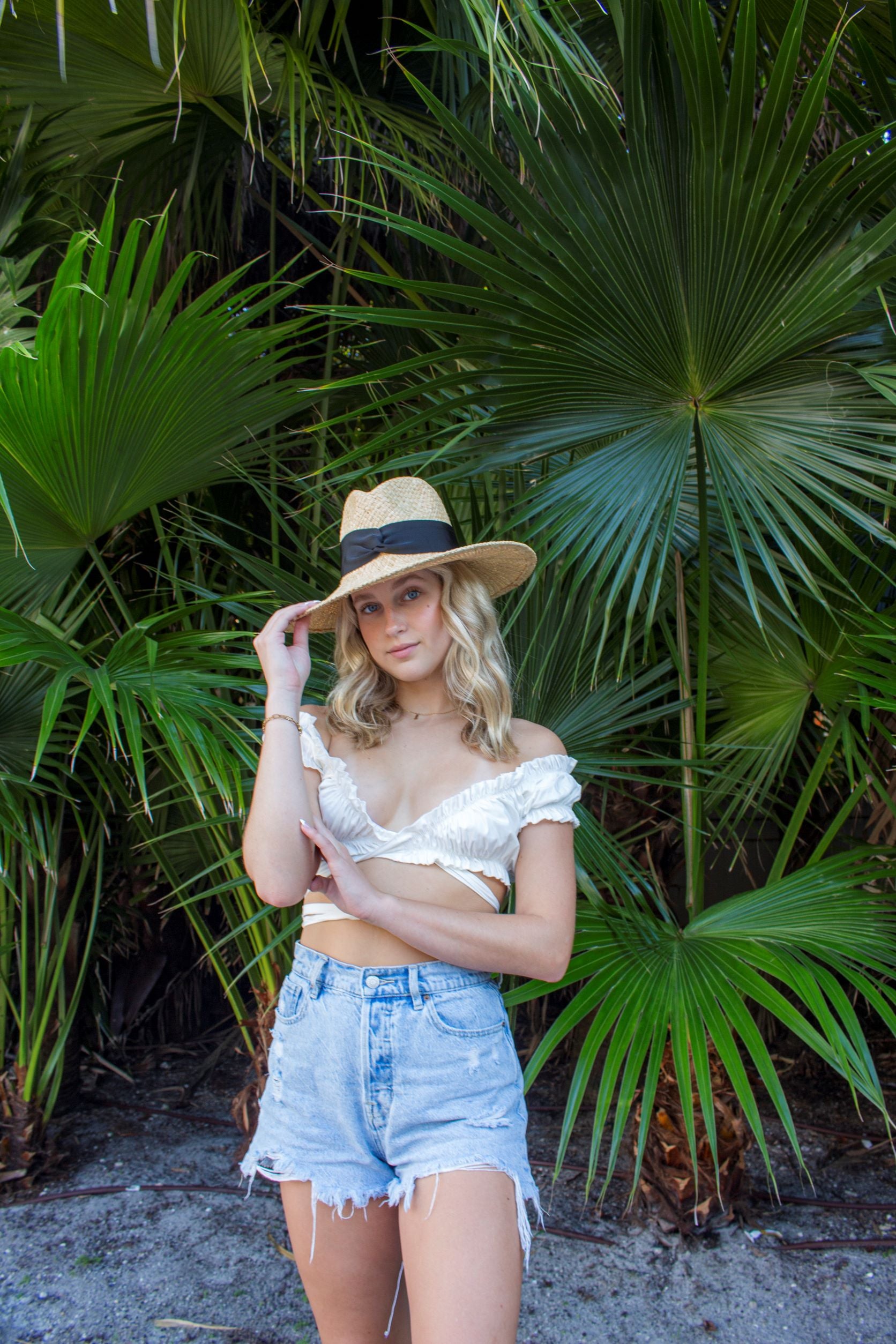 Person wearing raffia straw panama hat with black grosgrain tie