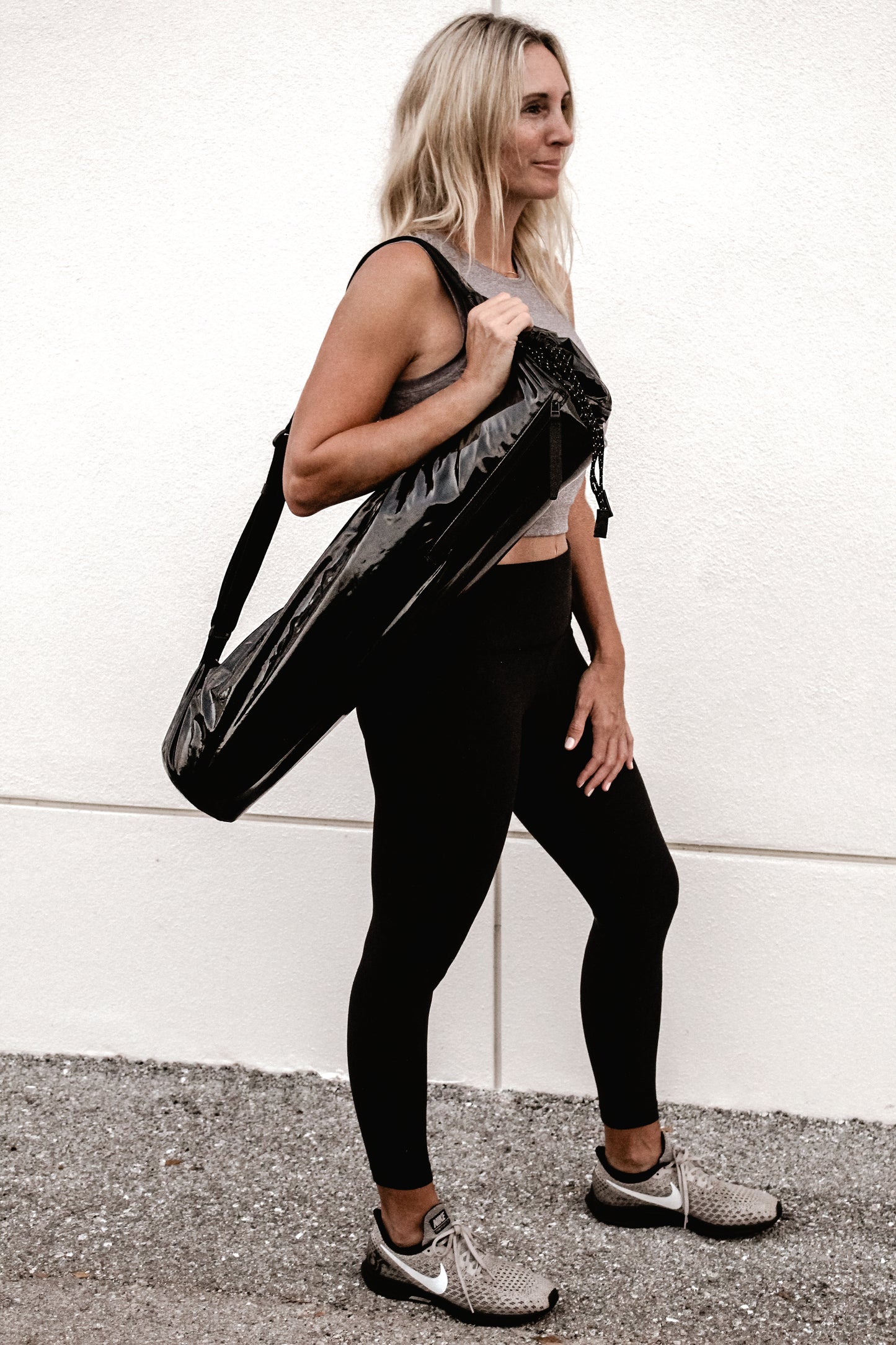 Person holding Anya & Niki glossy black yoga mat bag.