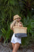 person holding natural raffia straw tote with linen lining and gray color block base.